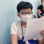 A boy reading a paper on his left hand