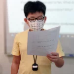 A boy reading a paper on his right hand