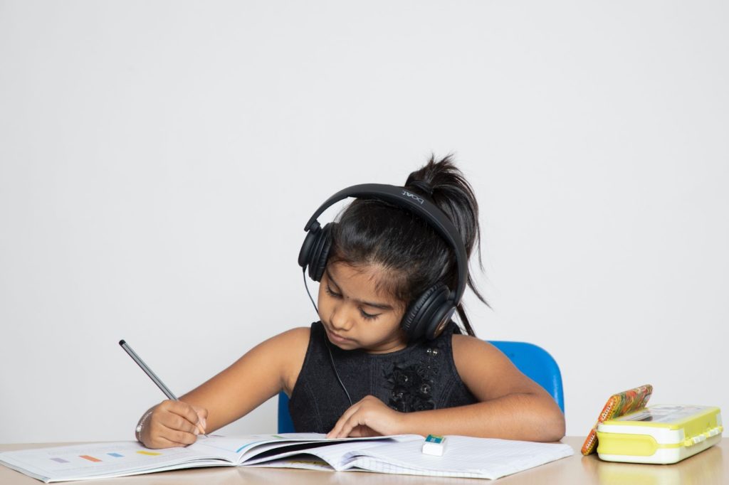 a girl holding a pencil on her right hand, drawing or writing on a book, learning for PSLE